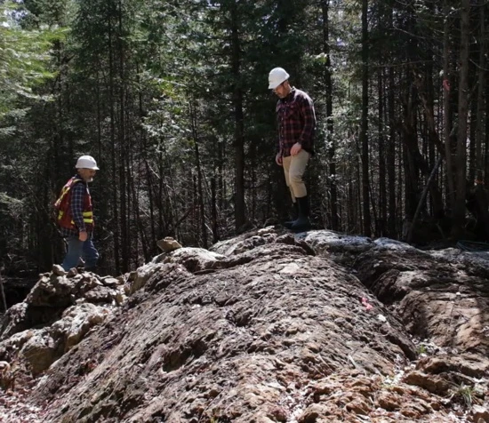 People examining exposed rock in an archival geological fieldwork photograph.